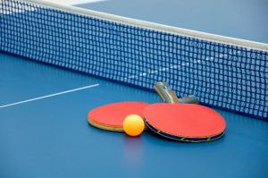 настольный теннис на столе у сетки ракетки и мяч