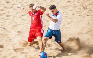 футболисты борются за мяч на песке